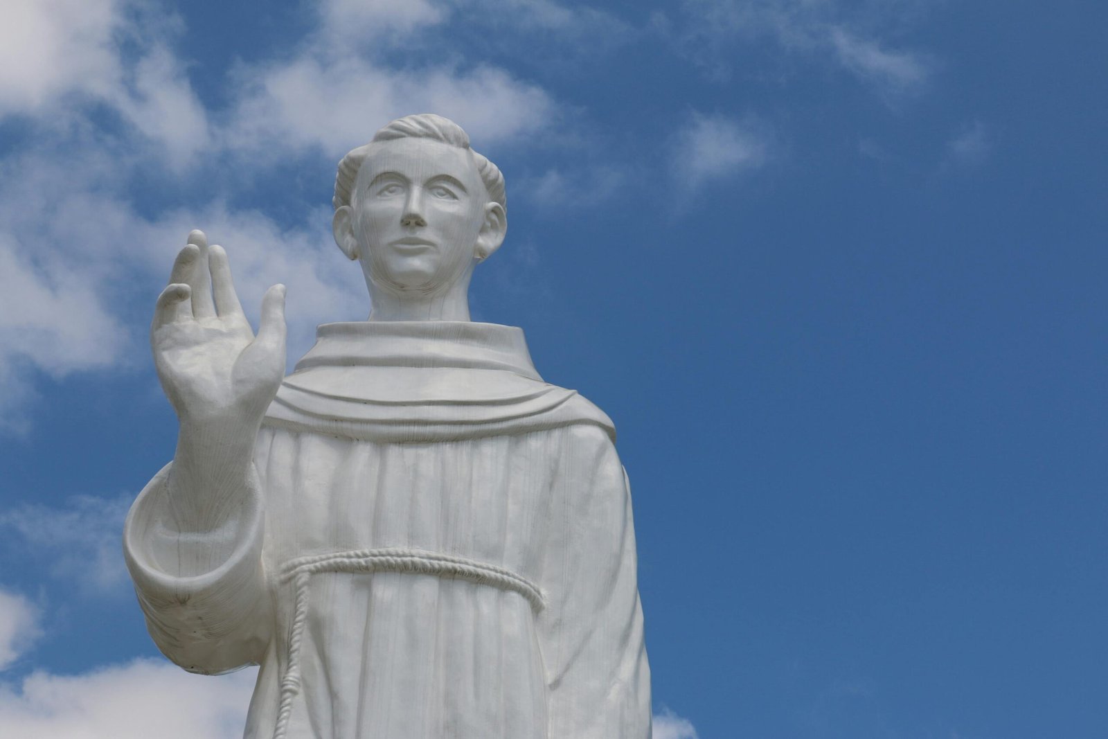 White marble statue of a saint against a vibrant blue sky in Guaratinguetá, Brazil.